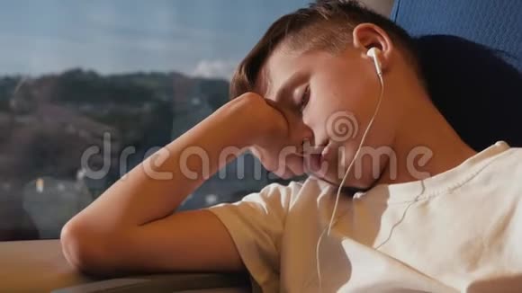 那个男孩在火车车厢的窗边睡觉这个男孩正在周游世界火车上的旅游男孩视频的预览图