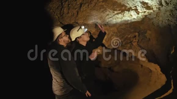 两个拿着手电筒探索洞穴墙壁的专家视频的预览图