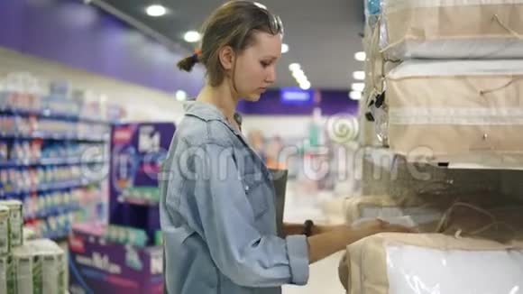 一个漂亮的女人在超市里选择枕头或毯子有选择的决心把包装产品从视频的预览图