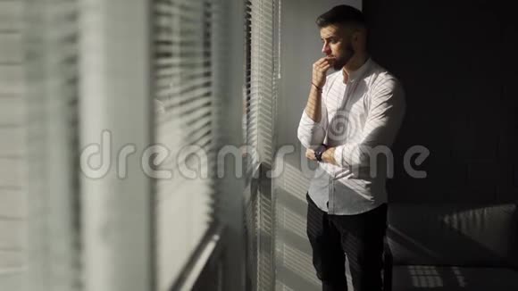 一个留着胡子的年轻人看着旺多在思考办公室里考虑投资的商人百叶窗和硬物视频的预览图