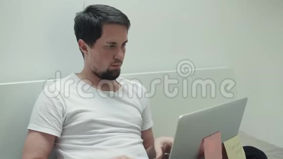 计算机科学家正在家里工作手提电脑坐在床上视频的预览图