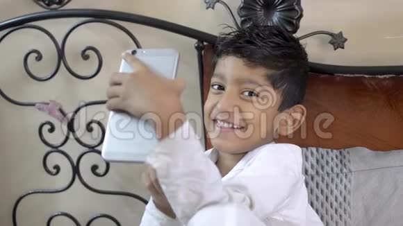 可爱的可爱的印度小白种人小孩在手机或智能手机相机上玩滑稽的自拍视频的预览图