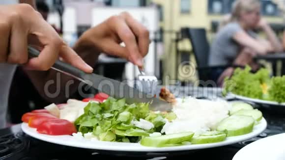 女孩切鸡肉串的特写并把烤串串在叉子与沙拉视频的预览图