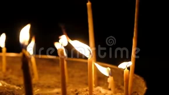在黑暗背景下教堂里的蜡烛在黑暗中燃烧镜头移动缓慢视频的预览图