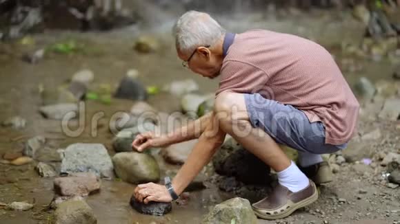老人在户外的石头上摩擦玛瑙视频的预览图
