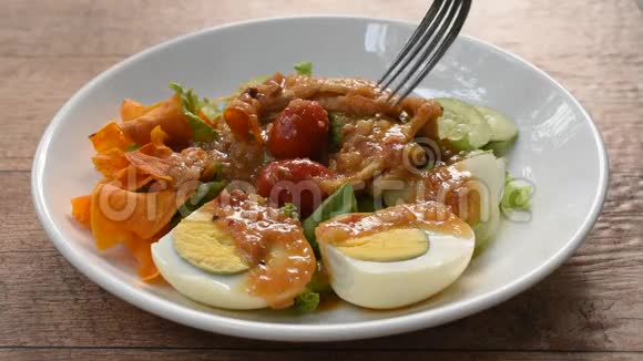 伊斯兰色拉蔬菜和煮鸡蛋打在脆炒芋头上调味甜豆酱清真食品用叉子刺在盘子上视频的预览图