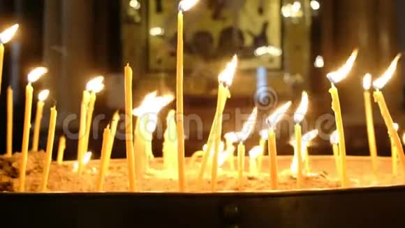 在东正教教堂的黑暗中蜡烛燃烧着一个古老的图标视频的预览图