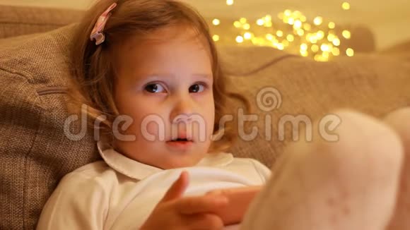 特写肖像儿童女孩在手机屏幕上观看并播放下载的应用程序视频的预览图