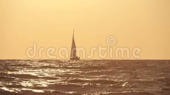 在日落的背景下航行游艇日落时分游艇在海洋中的轮廓游艇旅游浪漫之旅视频的预览图