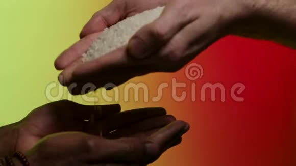白人的手把米粒交给另一只美洲黑人的手在明亮的背景下被孤立库存浇注视频的预览图
