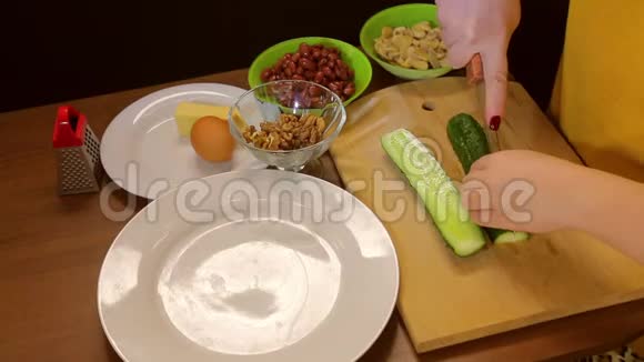 女性的手在木板上把新鲜黄瓜切成块视频的预览图