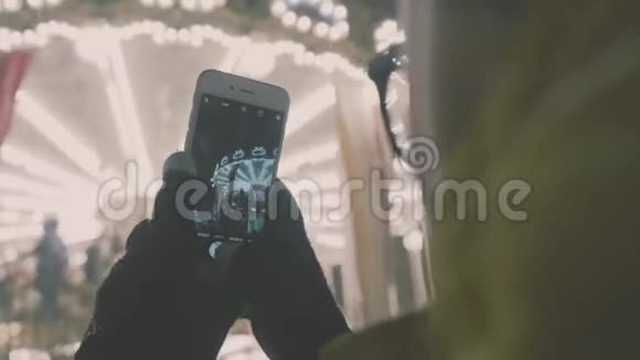 女子在智能手机上拍摄欧洲旋转木马场景4K女孩享受冬假季节视频的预览图