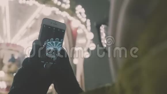 女子在智能手机上拍摄欧洲旋转木马场景4K女孩享受冬假季节视频的预览图