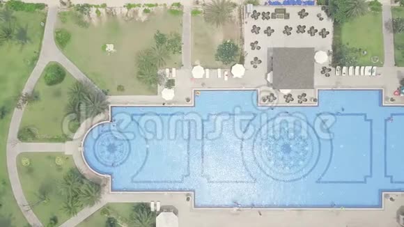 蓝色游泳池雨伞和绿色草坪在豪华度假酒店从上面的飞行无人机高空视野大视频的预览图