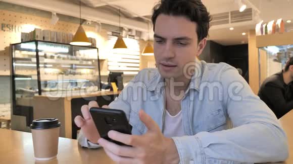 在咖啡厅使用智能手机和喝咖啡的年轻人视频的预览图