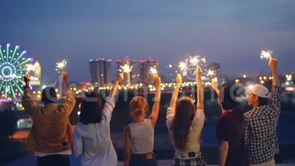 男子和妇女手持孟加拉灯举起双手站在屋顶上庆祝视频的预览图