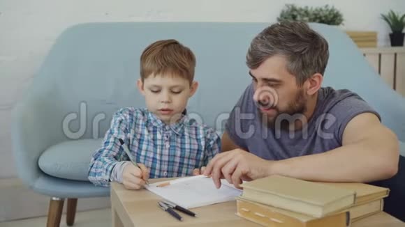 可爱的孩子厌倦了学习和娱乐而他关心的父亲激励他做家庭作业和写作视频的预览图