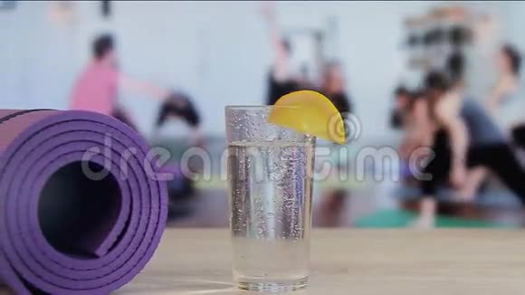 在杯子里倒一片柠檬加入水瑜伽普拉提集体运动视频的预览图