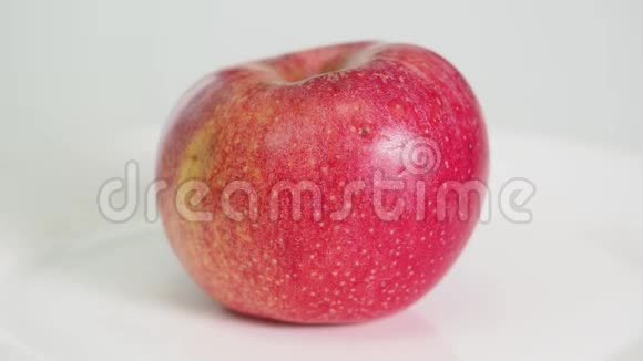 整个成熟的红苹果果实在白色盘子里旋转视频的预览图