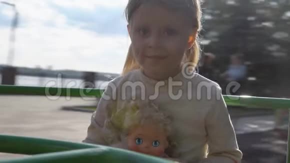 小女孩在公园里的旋转木马上骑着洋娃娃视频的预览图