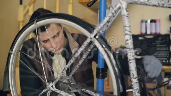 穿着休闲服和手套的有吸引力的机械师正在检查自行车车轮转动它看看机械自行车视频的预览图