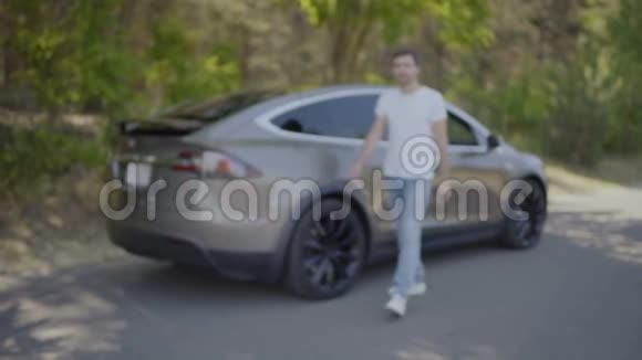 年轻人在现代汽车开门的模糊背景下展示汽车钥匙视频的预览图
