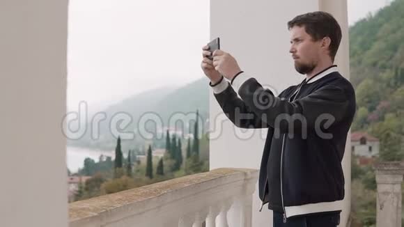男人在电话里拍风景照片他透过窗户看到视频的预览图