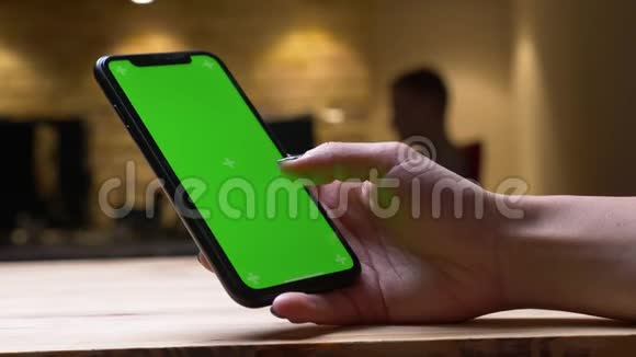 办公室室内绿色彩色屏幕的女性手在手机上滚动的特写后景拍摄视频的预览图
