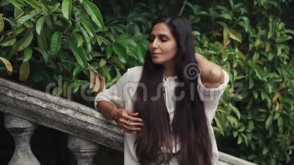 独自一人的阿拉伯女人站在热带花园里摸着她的长发视频的预览图