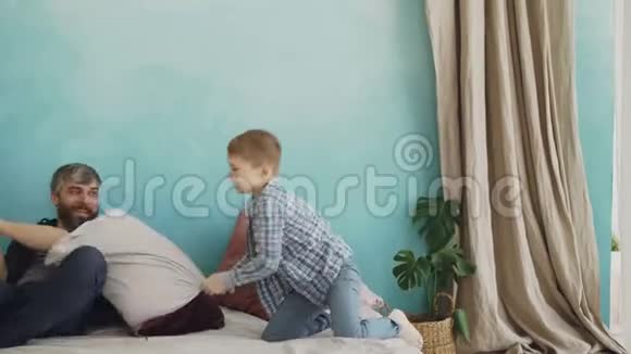 可爱快乐的父亲正在和他的小儿子玩打枕头笑着享受快乐的时刻爱视频的预览图
