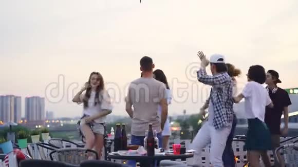 专业DJ在酷酷的屋顶派对中工作年轻的男女都在跳舞享受音乐视频的预览图