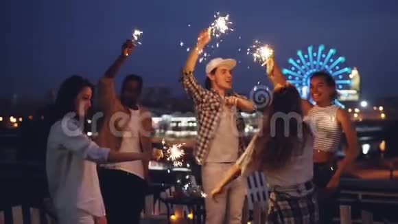 在晚上的屋顶聚会上兴奋的人们用燃烧的孟加拉灯跳舞一起玩得很开心视频的预览图
