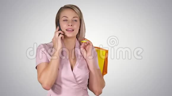 年轻女子带着购物袋在梯度背景下的手机上交谈视频的预览图