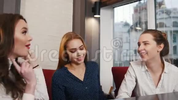 朋友们在酒吧见面三个微笑的年轻女人坐在咖啡馆里聊天视频的预览图
