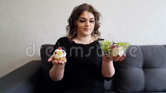全套女孩坐在沙发上慢镜头沙拉和蛋糕的选择饮食视频的预览图