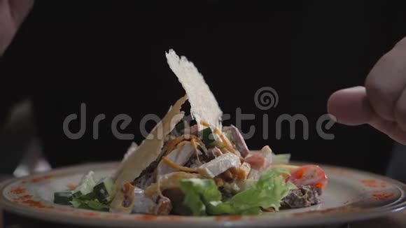 一个年轻人坐在一家餐馆的桌子旁吃蔬菜草药和肉的沙拉视频的预览图
