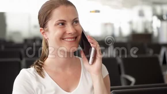 坐在机场候机室的年轻女子临时女商人与同事在手机上交谈视频的预览图