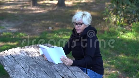 中年妇女在森林里看书视频的预览图