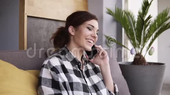 令人惊讶的是一个留着发尾和化妆的女孩坐在沙发上用电话交谈结束谈话视频的预览图