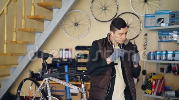集中修理工是润滑机构同时修理自行车在良好的车间穿暖和背心的年轻人视频的预览图