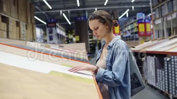 一个年轻的白种人妇女在一个大型超市在建筑材料和木材部门触摸木头视频的预览图