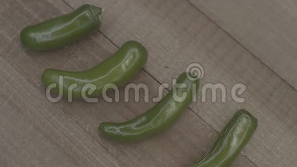 在木头上旋转的新鲜绿色辣椒的特写木头背景上的辛辣和新鲜辣椒健康素食视频的预览图