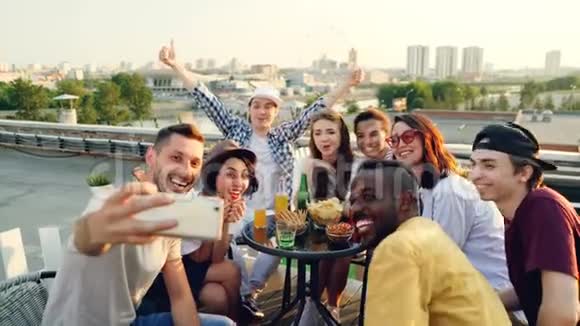 快乐的年轻男女们用智能手机摆姿势自拍笑着做手势庆祝视频的预览图