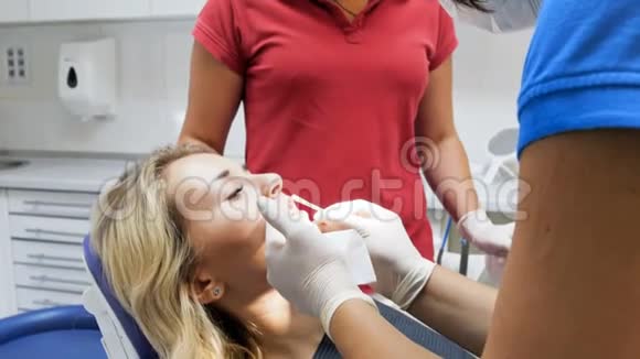 牙科医生在牙齿治疗前从病人口唇上取下口红特写4k视频视频的预览图