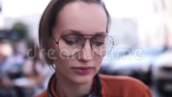 漂亮的近景一个年轻的金发女孩看着相机微笑着戴着一副时尚的现代眼镜视频的预览图