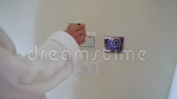 穿着白色外套的女人在酒店墙上的电源开关支架上插入电子钥匙卡然后按下按钮视频的预览图