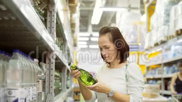 女人在玻璃碗里选择矿泉水超市里的女孩用绿色瓶子买水视频的预览图