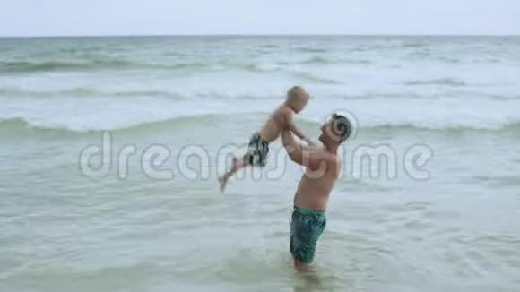 年轻迷人的父亲和他快乐的儿子在美丽的海滩上玩得很开心视频的预览图