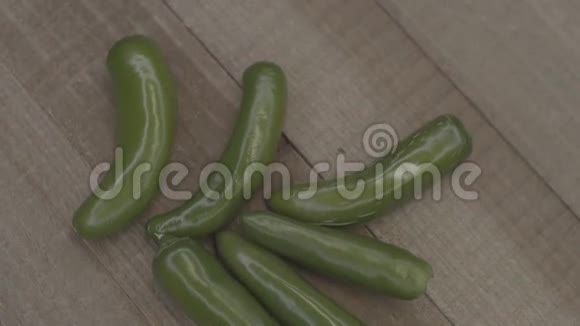 在木头上旋转的新鲜绿色辣椒的特写木头背景上的辛辣和新鲜辣椒健康素食视频的预览图