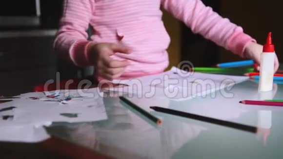 镜头向右滑动显示穿着粉红色毛衣的欧洲小女孩拿着铅笔在桌子上用文具画画视频的预览图